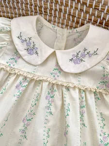 Détail du col Claudine avec broderie florale violette sur le body bébé crème