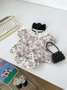 Flat lay of baby floral top and shorts set with black bow headband and vintage props