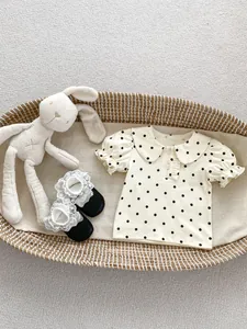 Detail of cream baby polo t-shirt with black polka dots, peter pan collar and puff sleeves