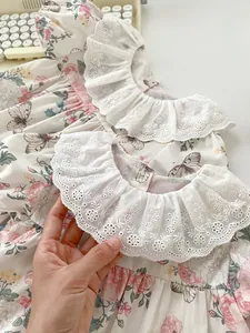 Close-up of floral baby romper featuring lace embroidery ruffled collar and rose print