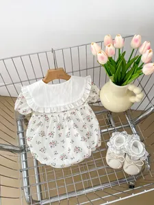 Detail of baby floral romper featuring a lace collar and matching bow crib shoes