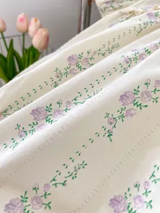 Détail de motifs floraux violets sur tissu crème doux pour barboteuse bébé
