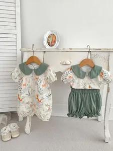 Detail of baby animal print romper and sage green shirt set on wooden hangers