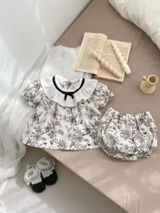 Detailed flat lay of baby floral outfit with ruffles, short sleeves and bloomers