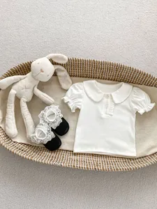 Detailed flat lay of baby short sleeve top with Peter Pan collar and ruffled details