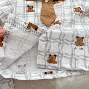 Detailed view of baby romper featuring plaid pattern, cute bear prints, and brown collar tie