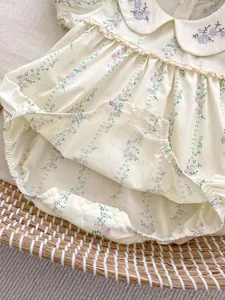 Détail du col Claudine avec dentelle et motif floral violet sur le body bébé