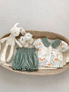 Flat lay of baby animal print shirt, green bloomers, and lace shoes in a woven basket