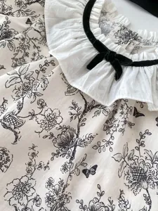 Detail of baby floral top with cotton ruffled collar and velvet bow tie texture