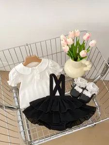 Flat lay of baby girl outfit with Peter Pan collar top and ruffled overall skirt in cart