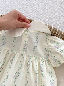 Détail d'un body pour bébé fille avec col Claudine et broderie de fleurs violettes