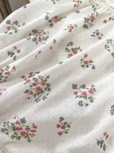Close-up of floral baby romper fabric showing delicate red and purple blossoms on cotton
