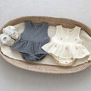 Flat lay of baby girl summer embroidered floral and plaid set in a woven basket