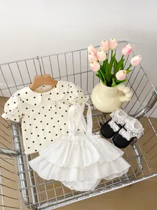 Detailed view of white polka dot Peter Pan collar shirt and ruffled suspender shorts set