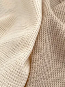 Dettaglio del tessuto in cotone a nido d'ape crema e kaki per abbigliamento neonato