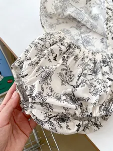 Close-up of baby bloomer pants with black floral toile de jouy pattern and elastic hem