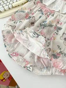 Detail of baby floral romper with white lace collar and bottom snap fasteners