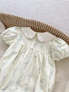 Détail d'une barboteuse à fleurs pour bébé avec col Claudine et manches bouffantes
