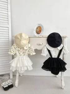 Detail of baby girl vintage outfit sets with polka dot shirts and suspender rompers
