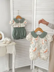 Detail of infant cotton romper and shorts set with forest animal prints and green trim