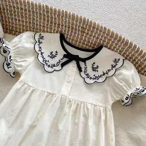 Detail of baby girl bodysuit with floral embroidered collar and navy scalloped edges