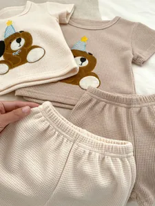 Dettaglio del set estivo in maglia a nido d'ape per neonati con ricamo di orsetto