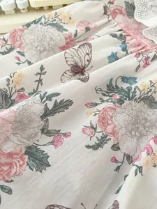 Macro detail of baby romper fabric with vintage floral print and delicate lace trim