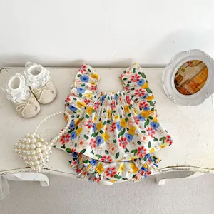 Detailed flat lay of floral baby summer set with ruffled top and bloomers on wooden desk