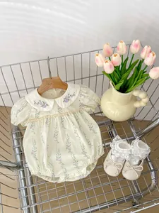 Détail d'un barboteuse à fleurs pour bébé et de chaussures dans un mini chariot