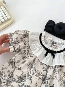 Detail view of baby girl floral outfit featuring large ruffle collar and velvet bow details