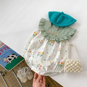 Détail d'un body bébé avec broderie de tulipes et col à volants vert pastel