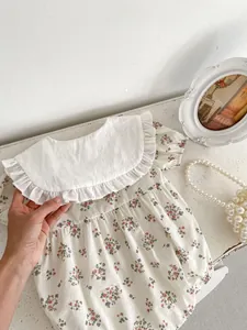 Close-up of baby floral romper with white ruffled collar and soft cotton texture
