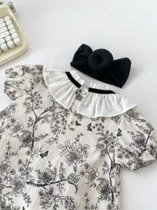 Flat lay of baby girl vintage ink floral outfit with ruffled collar and headband