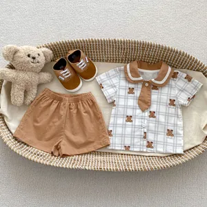 Infant summer set with bear print shirt, brown shorts, and tiny shoes in a woven basket