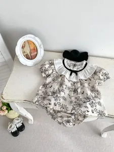 Detail of baby floral outfit set with ruffles and bow tie on white vintage wood table