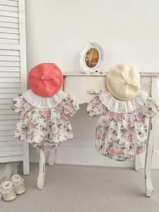 Detailed close-up of baby floral rompers with large lace collars and knit beret hats