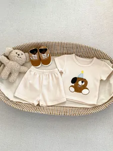 Dettaglio del set estivo in maglia a nido d'ape per neonato con ricamo di cucciolo in un cesto