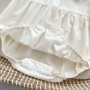 Detail of snap button closure on cream cotton baby bodysuit for easy diaper changes
