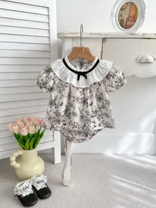 Detail of baby girl floral set featuring ruffled collar and black bow tie decorations