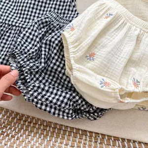 Detail of infant bloomers with black gingham and floral embroidery on cotton gauze fabric