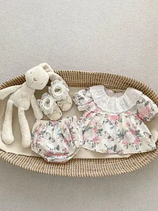 Flat lay of baby girl floral summer outfit with lace collar and matching shoes in a basket