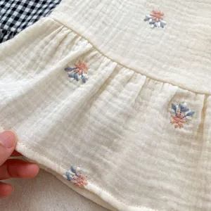 Detail of baby girl cotton gauze top with floral embroidery and wavy hemline texture