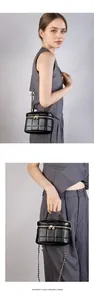 Detail of black quilted leather box bag with gold-tone hardware and chain strap