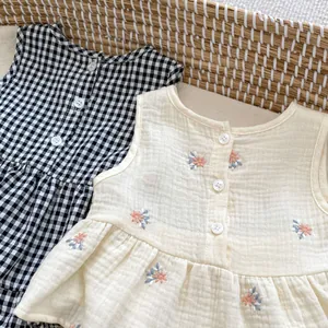 Detail of baby girl gingham top and floral embroidered muslin shorts in a woven basket