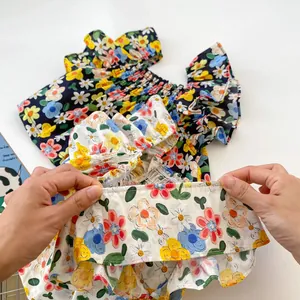 Detail of floral baby top featuring elastic pleated neckline and ruffled hem fabric