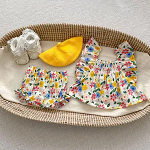 Flat lay of floral baby summer set with sleeveless top, shorts, hat, and lace shoes