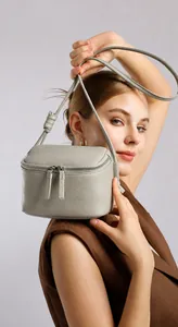 Sac bandoulière en cuir véritable gris clair avec texture souple porté sur l'épaule de côté