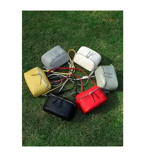 Sacs à bandoulière en cuir grainé de plusieurs couleurs disposés sur une herbe verte