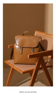 Dettaglio zaino in pelle cerata con fibbie metalliche su sedia in rattan vintage