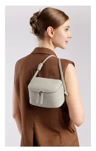 Détail du sac carré en cuir grainé gris clair avec double fermeture éclair et bandoulière